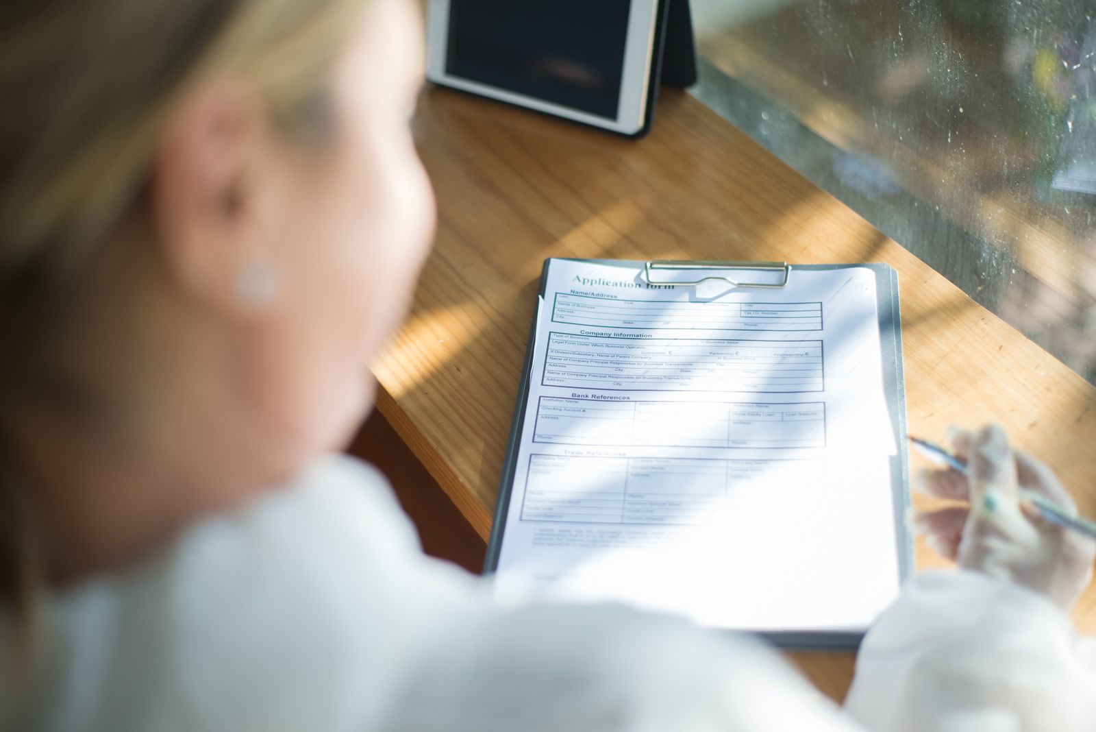 Person filling out an application form on a clipboard